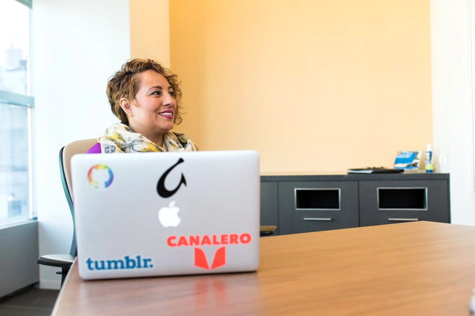 Una manager sorridente che lavora al suo laptop in un ambiente luminoso e moderno.